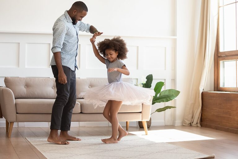 A father and daughter dancing in a bright Lexington Homes living room