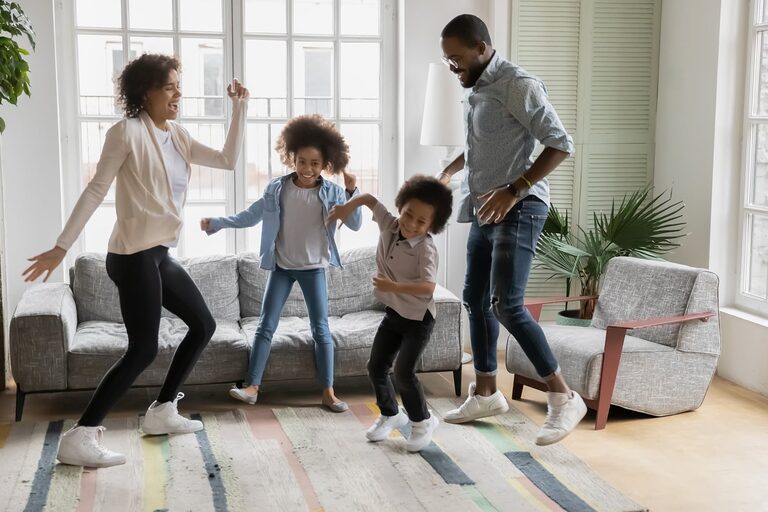 A family dancing together in a sunlit living room of a Lexington home